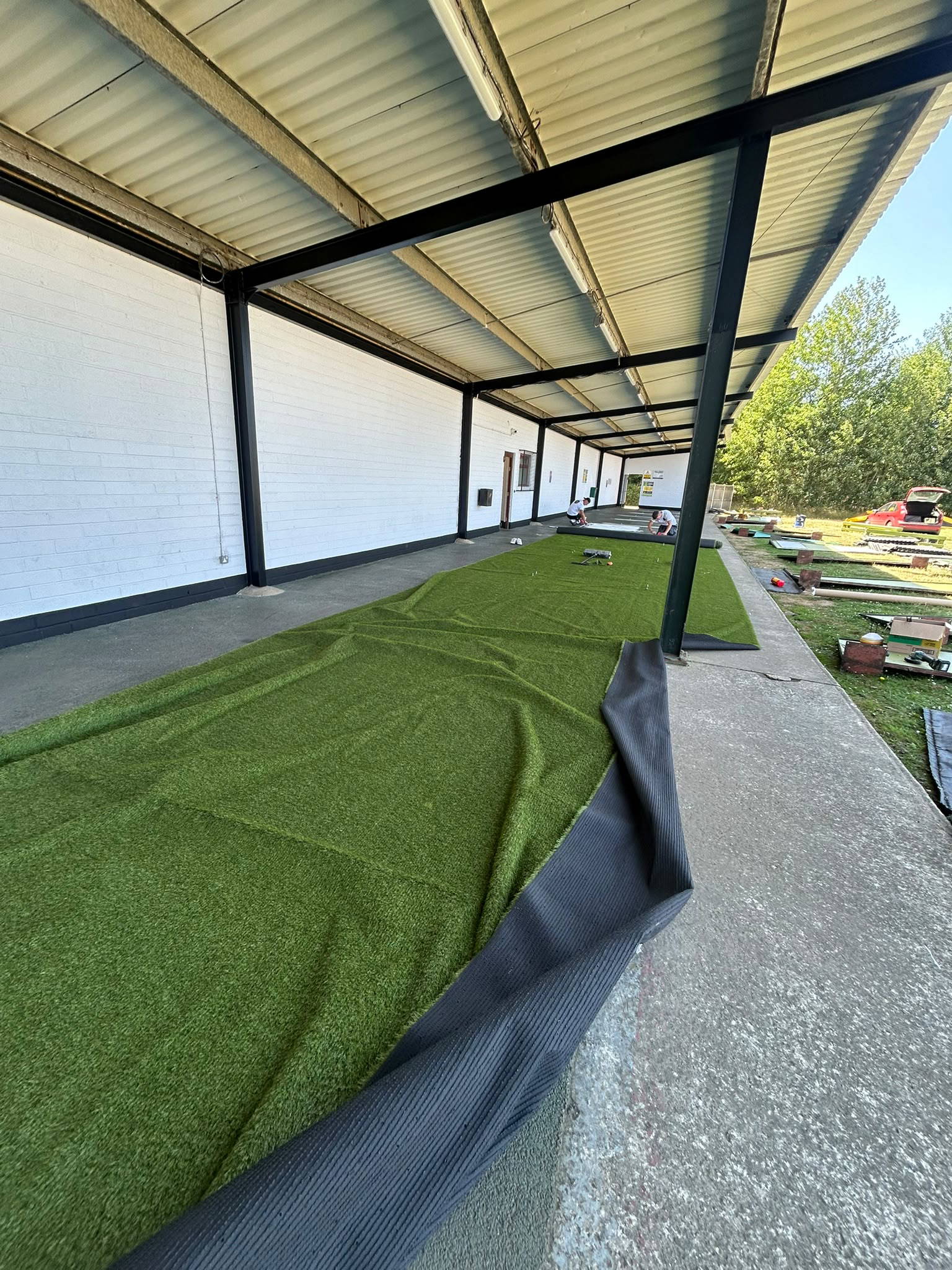 New artificial turf being fitted in the driving range bays